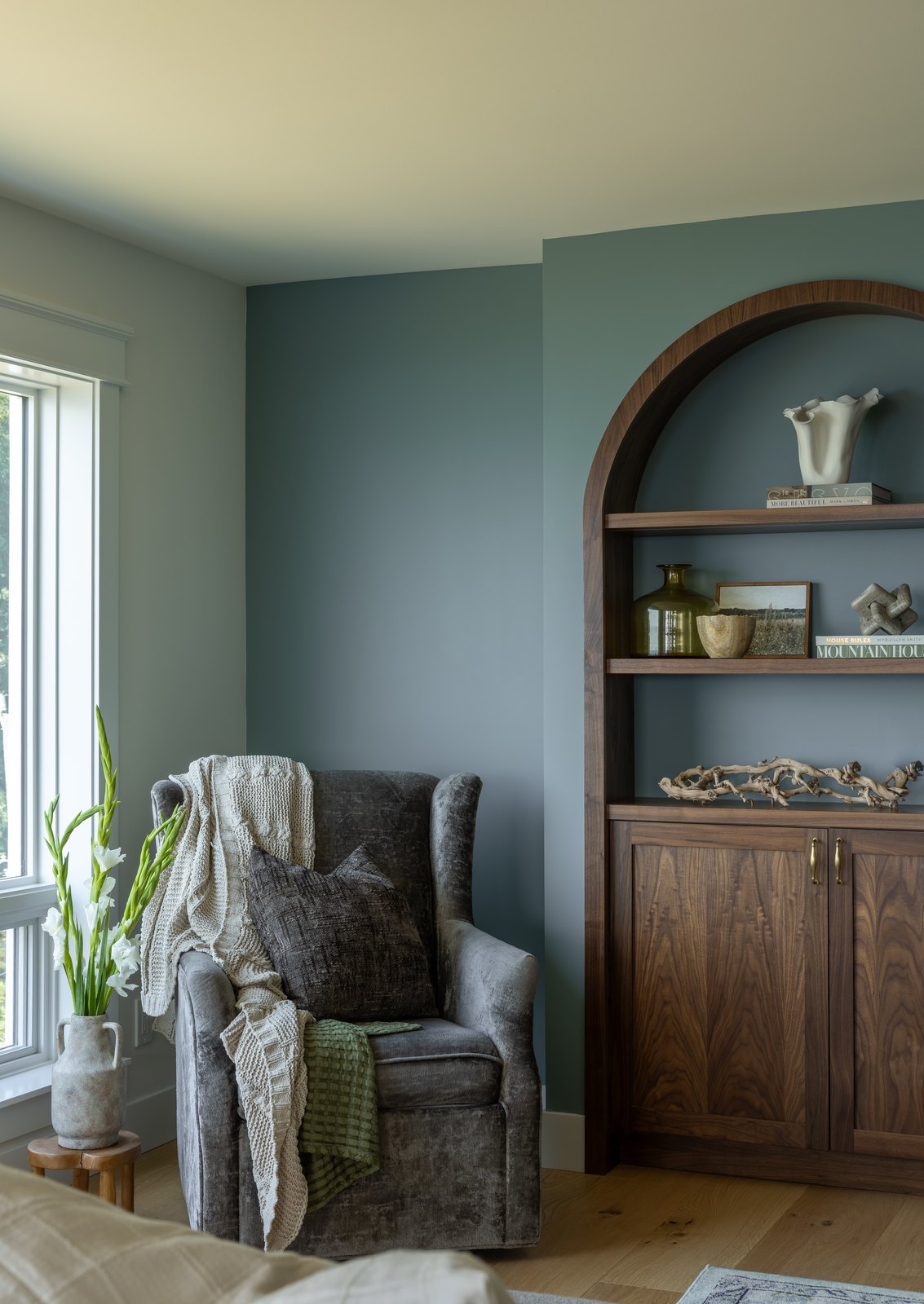 Reading chair beside an arched built-in on a blue accent wall