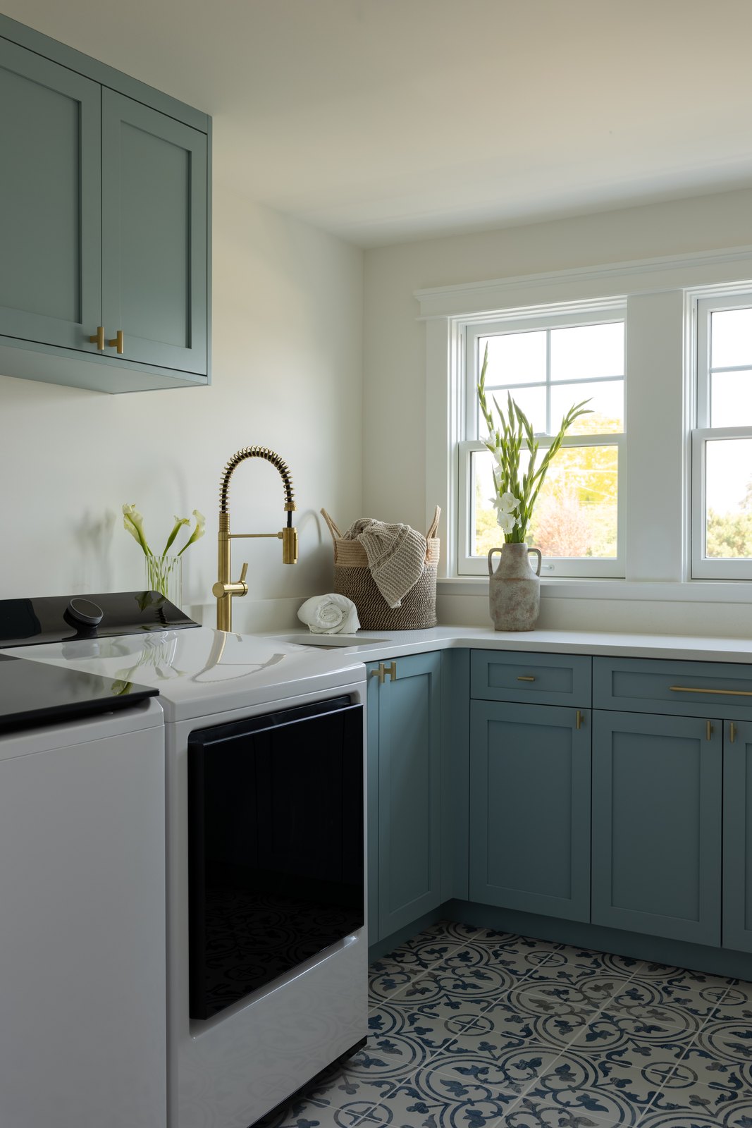 Patterned floor tile and painted cabinetry in the laundry room.