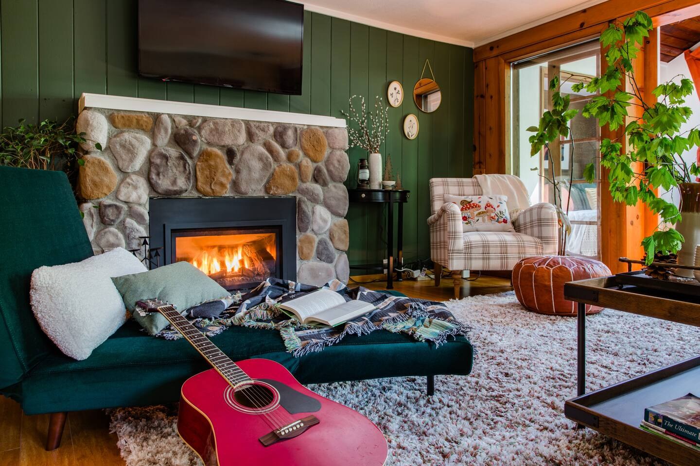 Living room of a North Bend short-term rental with a stone fireplace and green paneled walls